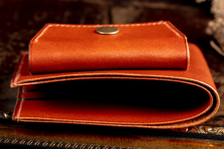 Part of a brown leather wallet or case with stitching.