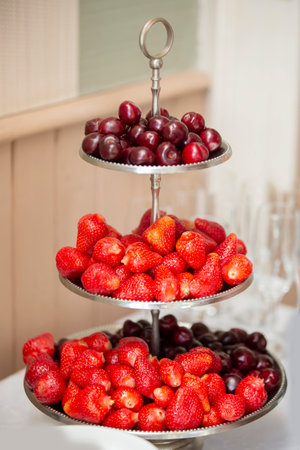 Summer strawberries and cherries are stacked in a beautiful plate for a buffet table in a restaurant.の写真素材
