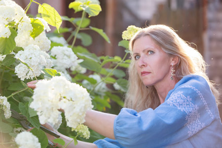Beautiful elderly woman posing in the garden with a bouquet of flowers.の写真素材
