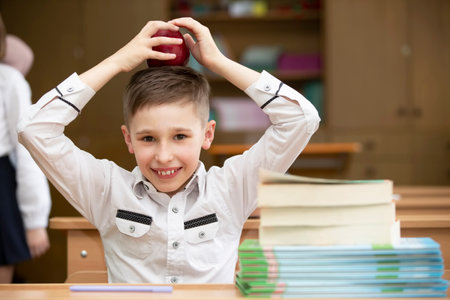 Schoolboy at the desk. Boy in the classroom with books and an apple. Secondary school. Back to...