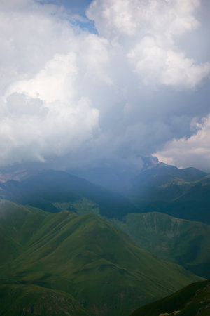 Mountains in clouds and clouds. Aerial view of a mountain peak with green trees in the fog.の写真素材