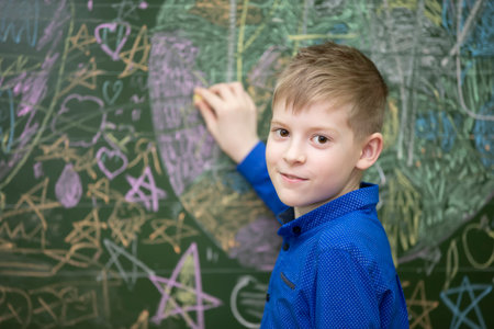 The face of a happy schoolboy at the blackboard close-up.の写真素材