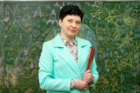 Portrait of a school teacher with a magazine at the blackboard.の写真素材