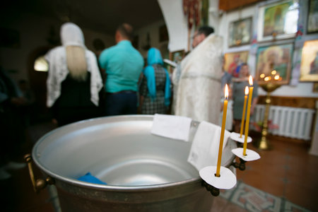 Blurred Orthodox on the background of the font for the baptism of the baby.