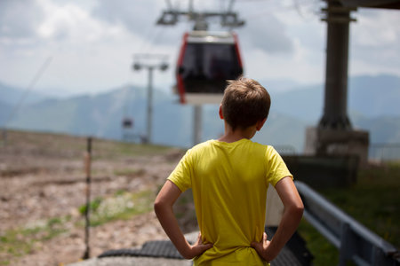 A boy in a yellow T-shirt looks at the cable car.の写真素材