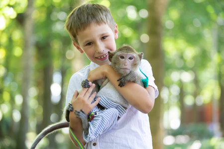 A happy boy holds a little monkey in his hands.