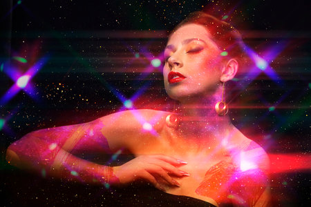 Glamorous girl with art make-up in the rays of light glitter dances with her eyes closed. Night club...