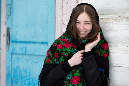Portrait of a beautiful girl in a Russian headscarf. Young woman . Russian village in winter.
