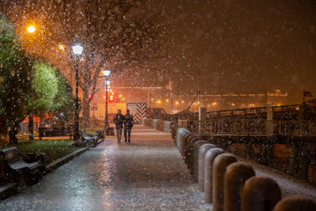 Snow-covered background of the night city with random passers-by.