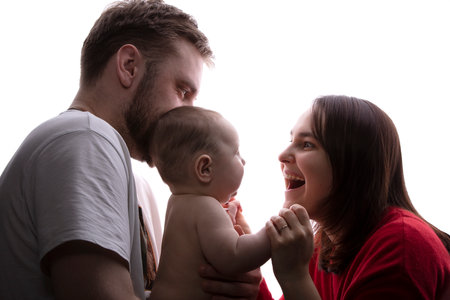 Close up portrait of young parents and baby. Father and mother hug and play with a beautiful little...
