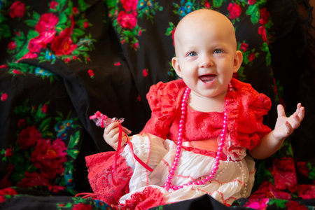 Funny little girl under one year old with beads smiles and looks at the camera. Little fashion-girl.の写真素材