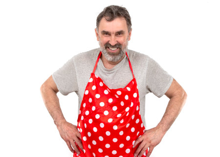 An elderly bearded man in a red polka-dot culinary apron on a white background.の写真素材