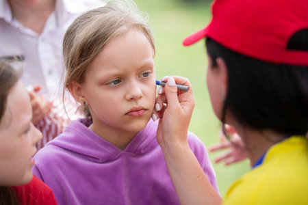 May 27, 2021.Belarus.Yagodnaya village. Children's holiday. Makeup artist draws face painting on a child's face.のeditorial素材