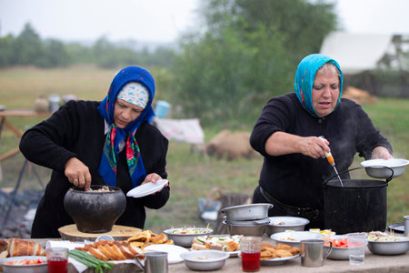 Belarus, Gomel region, July 20, 2022. Refugee camp. Refugee women prepare food outdoors in a refugee camp.のeditorial素材