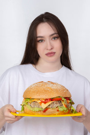 A woman is holding a big barbecue hamburger sandwich on the background. Fast food concept. The girl has a huge hamburger.の写真素材