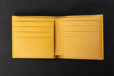 Leather products. Wallet business card holder made of yellow leather on a black background.