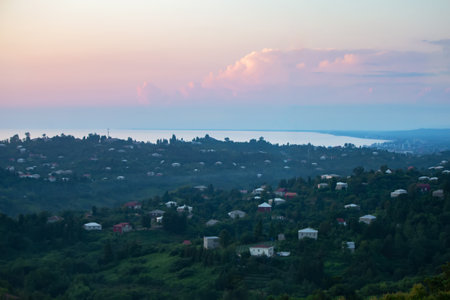 Beautiful tourist landscape of a mountainous area with a small house and a colorful sky. Mountains of Georgia and the sea in the distance.の写真素材