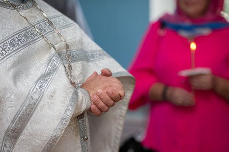 Folded hands of an Orthodox priest in a cassock.