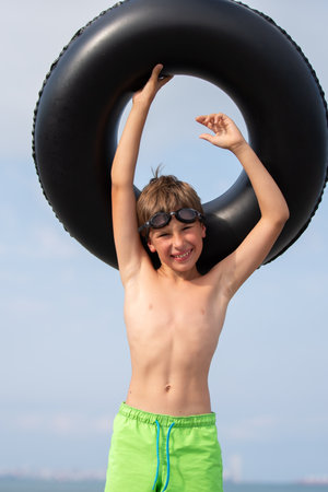 Happy boy wearing swimming goggles and an inflatable swimming ring.