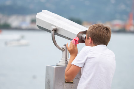 The boy looks at the observation deck in a tourist handheld telescope.