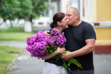 A happy elderly couple with a bouquet of flowers walks around the summer city.の写真素材