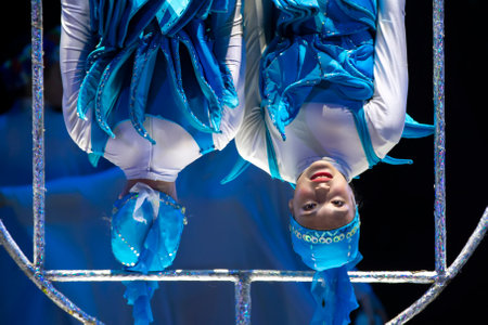Two acrobat girls show a circus number on a dark background. Acrobatic performance.の写真素材