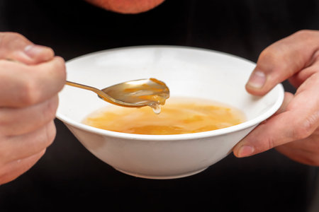 Hands holding a plate of chicken soup and a spoon.の写真素材