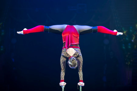A tightrope walker acrobat girl performs and does the splits.