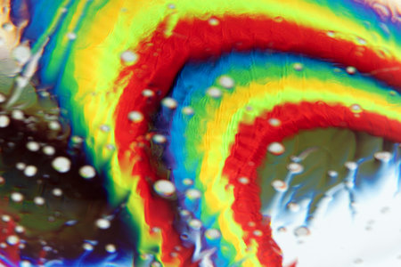 Optical abstract background of rainbow fabric with kinks and light effects in water drops.