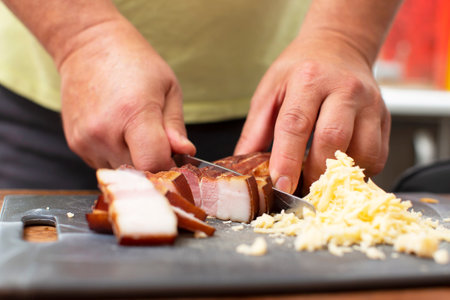 Man's hands cut a piece of pork bacon.の写真素材