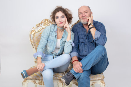 A funny portrait of an adult daughter and an elderly father in denim clothes on a gray background.の写真素材