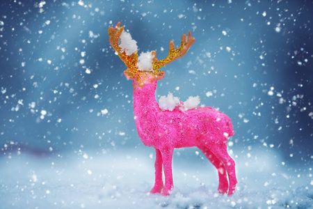 A Christmas card. Pink toy Christmas deer on a blue winter background.の写真素材