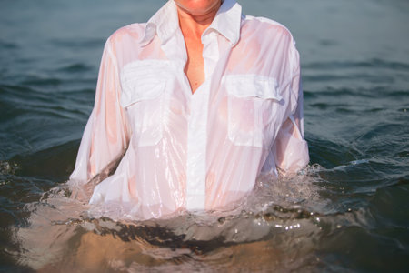 An unrecognizable woman in a white shirt comes out of the seawater.の写真素材