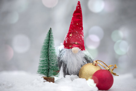 A Christmas card. Cute dwarf in a red hat on a winter background.の写真素材