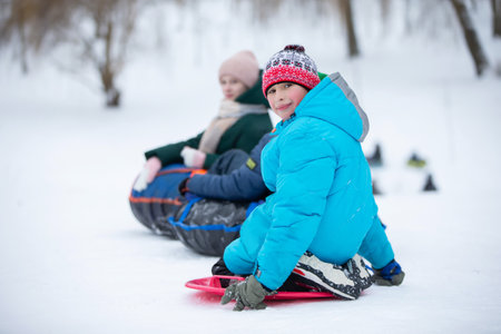 Children ride tubing down a snow slide.の写真素材