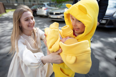 A mother gives her newborn baby to his brother to hold.の写真素材