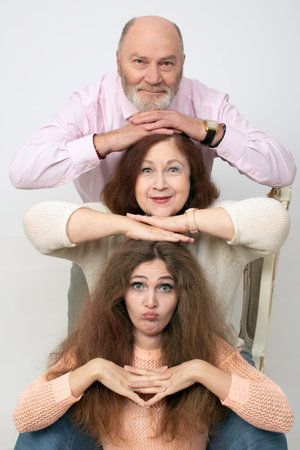 A creative family portrait of elderly parents and an adult daughter.