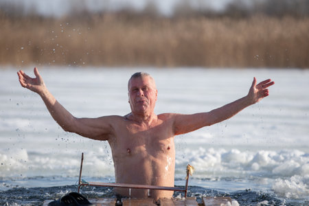 An elderly man bathes in an ice hole on the Orthodox feast of the Epiphany. Take a dip in the icy water.の写真素材