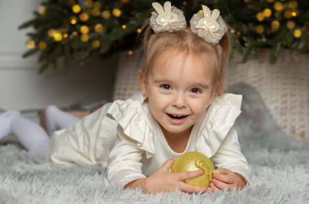 Happy girl with golden Christmas ball on Christmas Eve.の写真素材