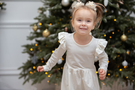 Happy little girl on Christmas holidays. The child runs and has fun near the Christmas tree.の写真素材