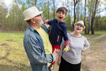 Grandfather, grandmother and grandson are having fun outdoors.の写真素材