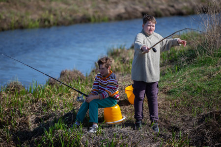 Two teenage boys fishing in a small river.の写真素材