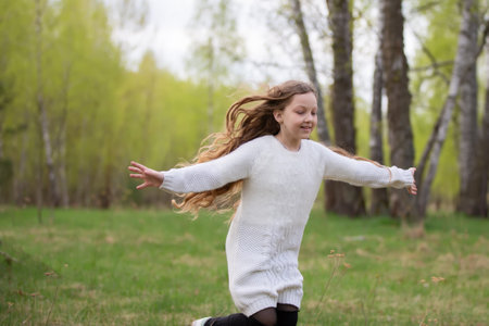 A little girl runs through the spring forest. A child on a walk in the park.の写真素材