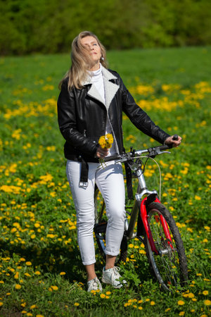 An adult woman rides a bicycle through a spring meadow and enjoys the moment.の写真素材