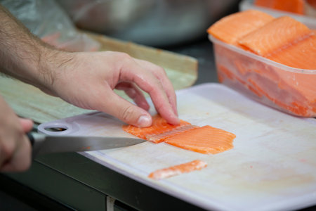 Human hands are slicing red fish with a knife.の写真素材