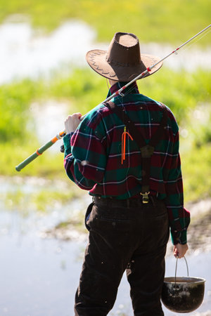 An adult man with a fishing rod goes fishing.