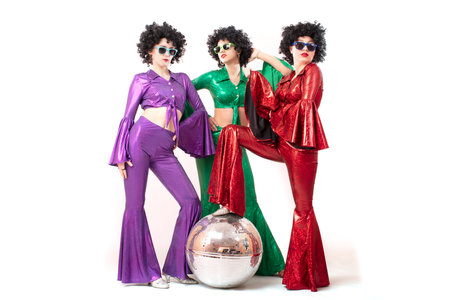 Three female pop stars in neon clothes pose in front of a silver ball. The women wear colorful clothes and eighties-style sunglasses.の写真素材