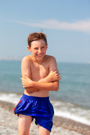Funny boy in wet shorts on the beach. He is frozen.の写真素材