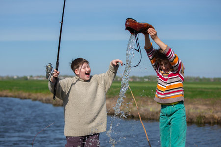 Funny fishing. Two of the boy's friends hooked an old shoe with a fishing rod and are laughing.の写真素材