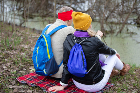 Active elderly Caucasian couple hiking with backpacks and hiking poles enjoying their adventure. They sit with their backs to the camera.の写真素材